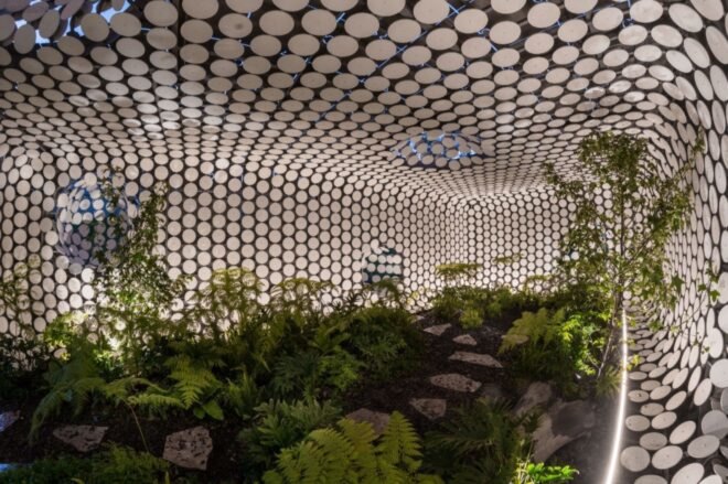 a different view of inside the building, the interior is a lush, green plant-filled area. circular cut-outs make up the interior walls