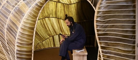 person sitting on a bench inside a seaweed pavilion