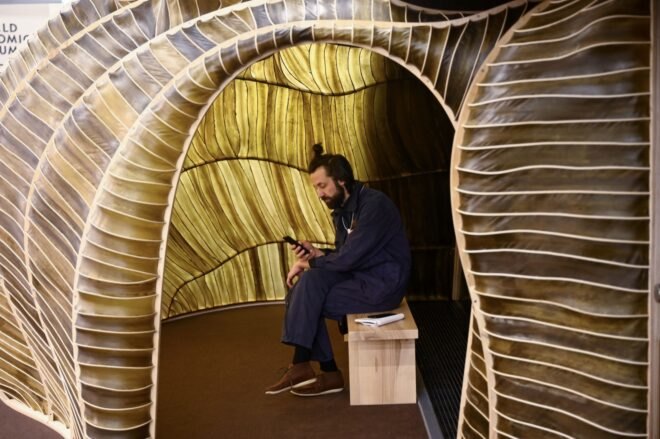 person sitting on a bench inside a seaweed pavilion