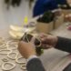 person attaching seaweed to wooden circle
