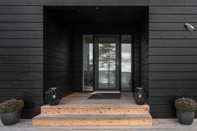 a close-up of a door, surrounded by black paneled facade.