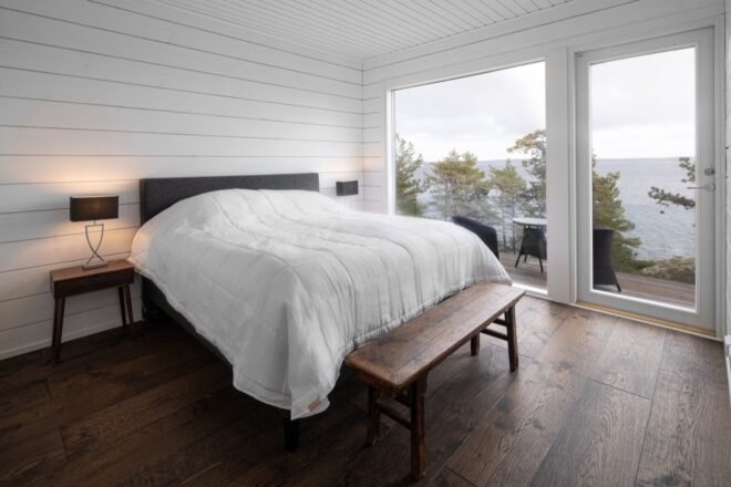 a second bedroom with a balcony that looks out on a body of water and trees.