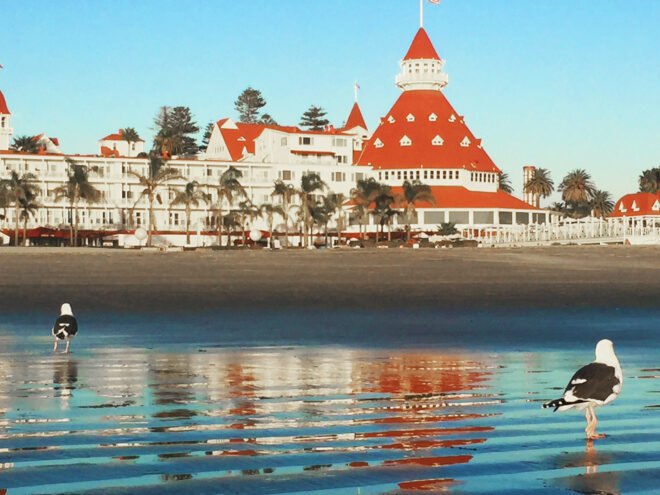 a beachfront in front of a hotel with white walls and an orange-red roof