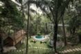 a lush area with thatched roof buildings and a pool