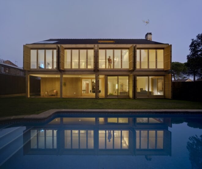 tan home with several large windows lit from within at night