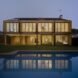 tan home with several large windows lit from within at night