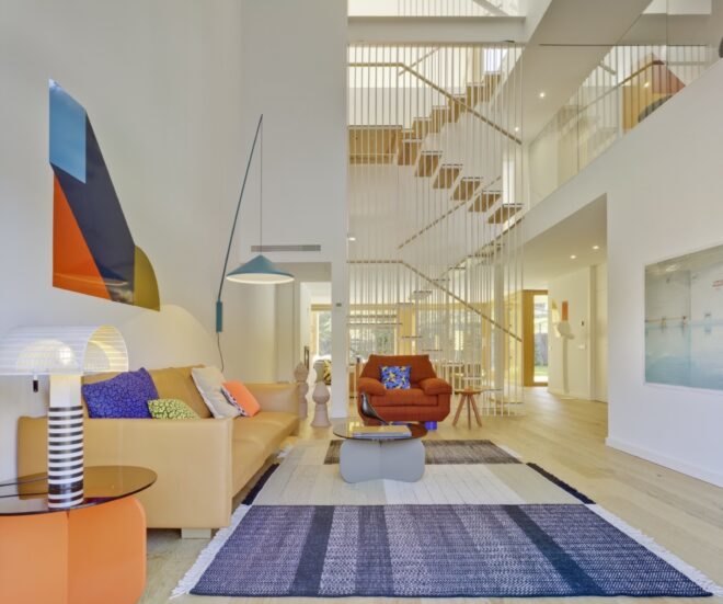 living area with red chair, tan sofa with colorful pillows and a blue rug