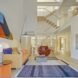 living area with red chair, tan sofa with colorful pillows and a blue rug