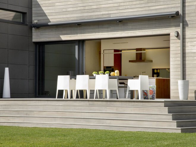a raised patio with a table and white chairs