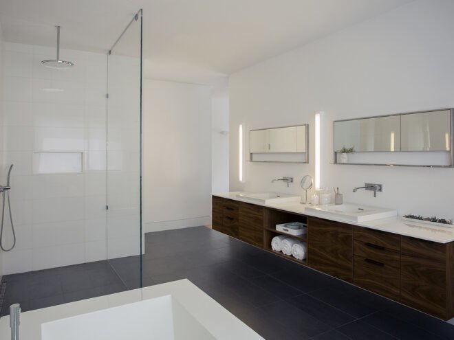a bathroom with a shower on the left and sinks and cabinets on the right