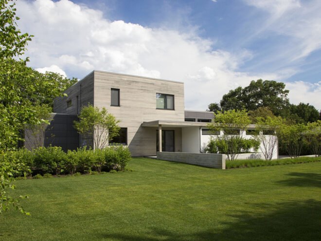 a house with a green lawn in front and blue, cloudy sky above