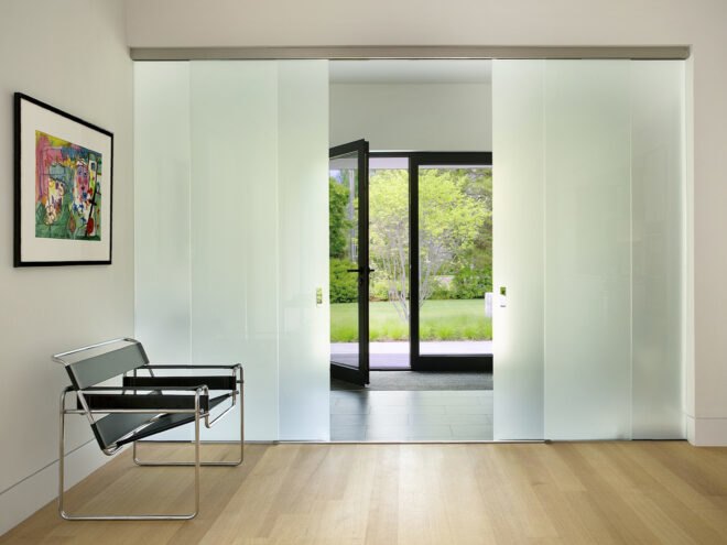 the entrance to a house from indoors. to the left in the entranceway is a sofa with a painting above it on the wall