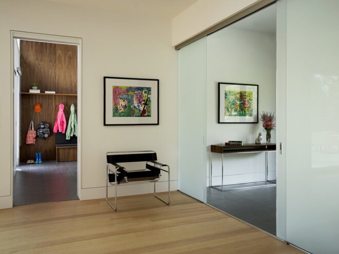 the entranceway to a house with wood floors and white walls decorated with paintings