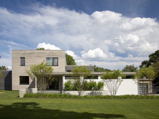 a house with a green lawn in front and blue, cloudy sky above