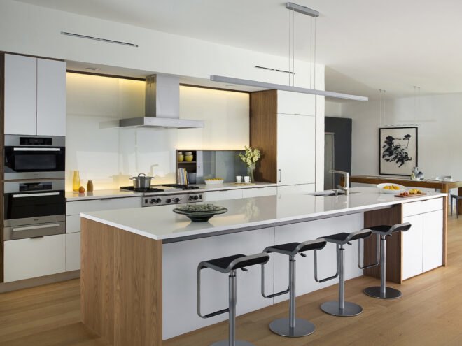 a kitchen with white cabinets and an island with white countertops and four barstools sitting at it