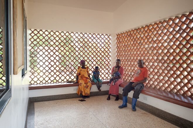 people sitting on benches near perforated brick walls