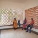 people sitting on benches near perforated brick walls