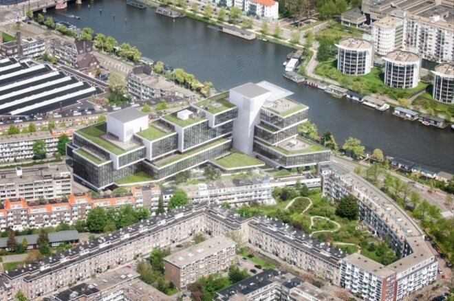 a bird's-eye view of the new Rivierstaete building, showing the city, trees and river. the new building features green rooftops