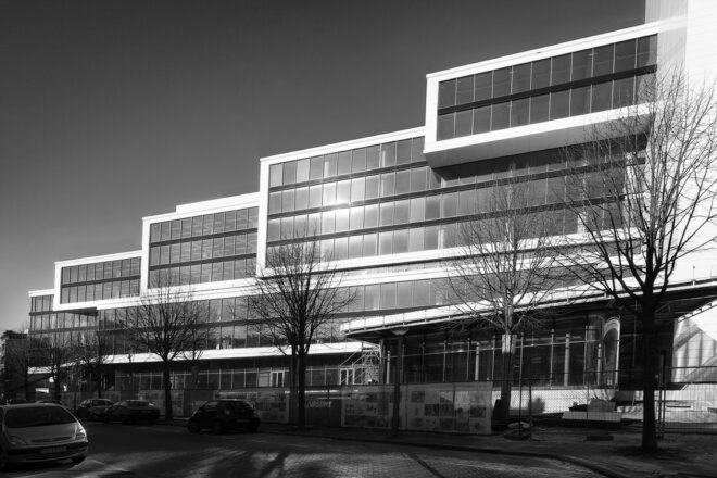 a black and white photo of a front view of a tired building with facade covered in windows