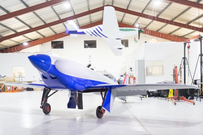 a side angle of a small plane with blue detailing. another plane hangs from the ceiling