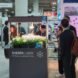 a picture of a Sherpa Light booth at CES 2020. green plants are mounted on a gray box labeled 