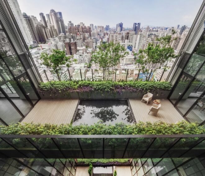 chairs on wood patio by reflective pool with city skyline in the background
