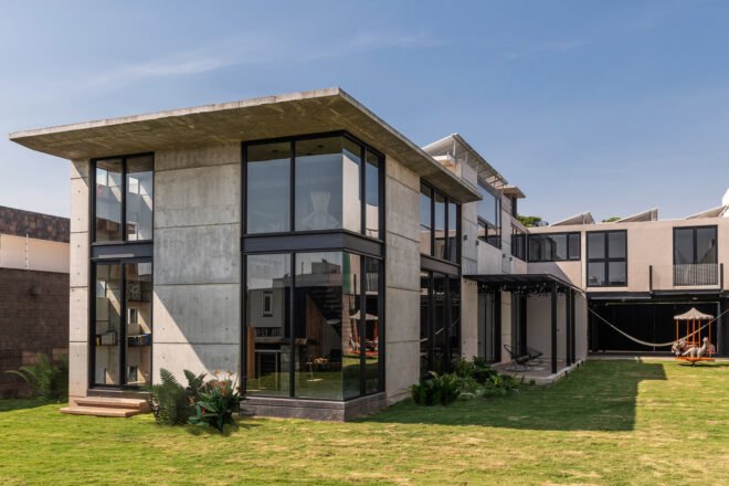 flat roofed home with several windows and a green lawn surrounding it
