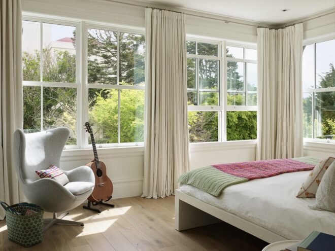 large white bed facing massive windows with views of trees
