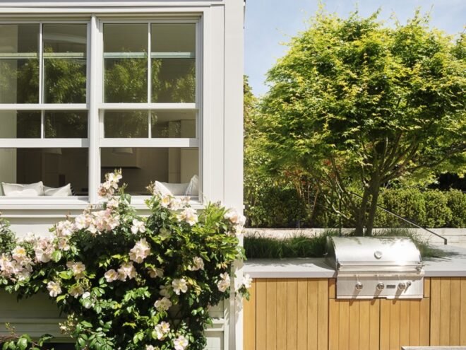 flowering bush growing in front of window of a white home