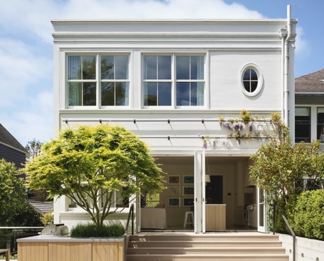 historic white home with two trees growing in front of it