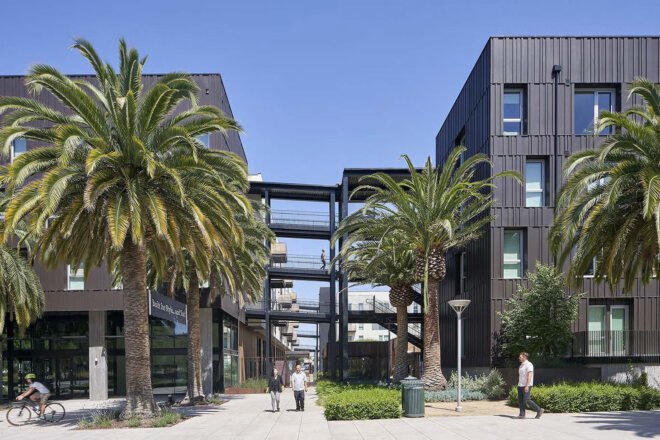 two dark buildings with walking structures connecting them. trees surround the building
