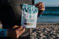 person on beach holding package of kelp jerky