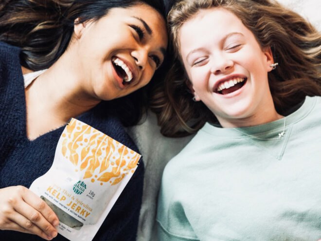 two people laughing and holding kelp jerky