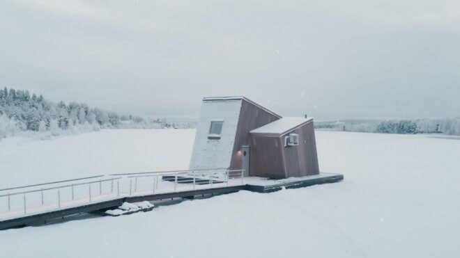 a wooden cabin with slanted volume on a frozen landscape