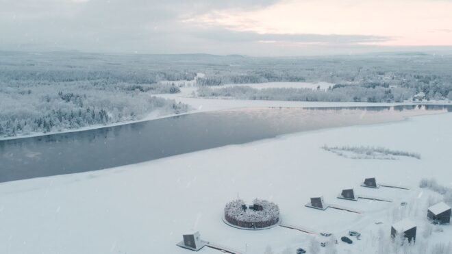 a circular building and several cabins on a frozen landscape