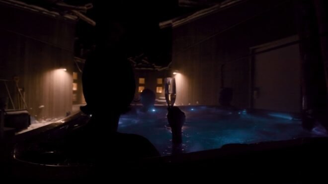 person with champagne flute in a pool at night