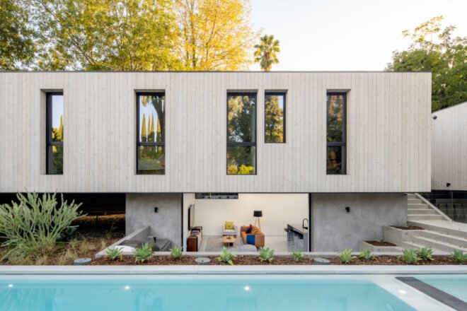 long, narrow wood home beside a rectangular swimming pool