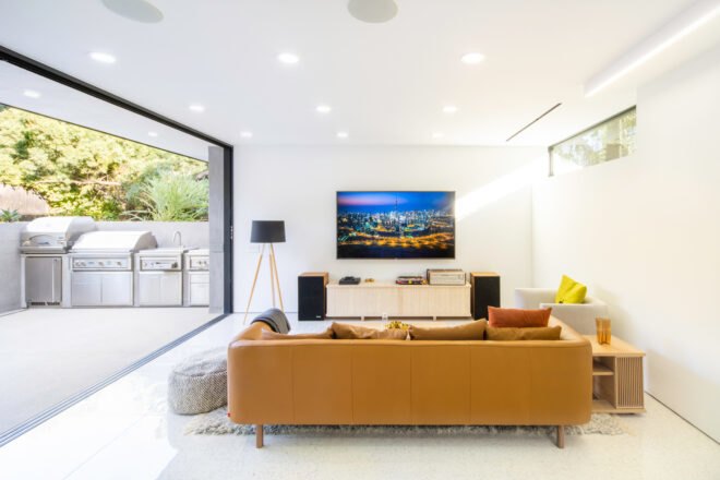 yellow couch facing a television in white room