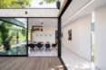 white dining room with glass wall open to wood patio