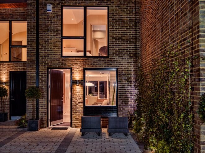 patio furniture on patio outside a brick home lit from within at night