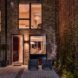 patio furniture on patio outside a brick home lit from within at night