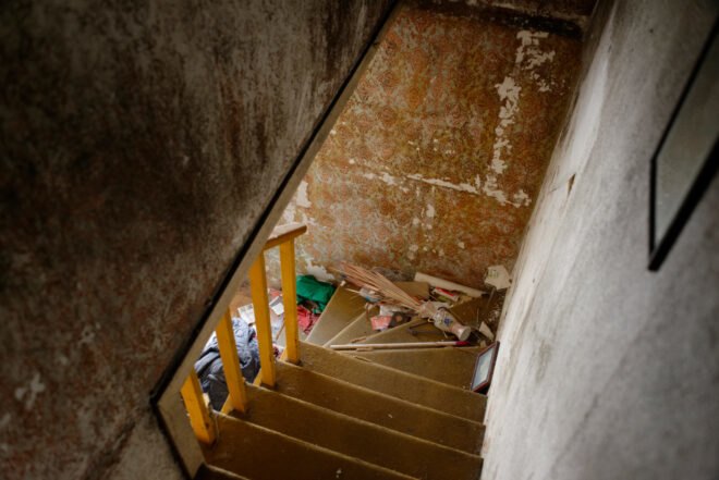 before image of old home with carpeted staircase and peeling wallpaper