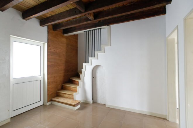white room with wood ceiling beams and wood spiral staircase