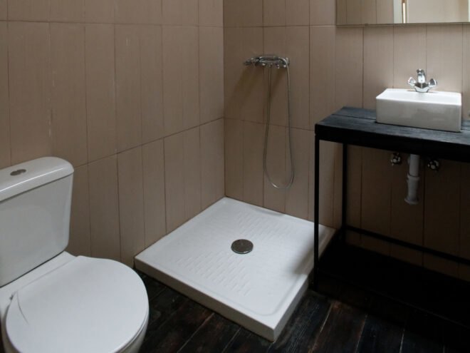 bathroom with dark floors, tan tiled walls and an open shower