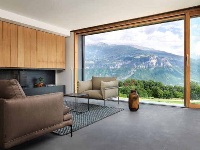 living area with beige sofa and chair and a glass wall framing mountainous views