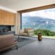 living area with beige sofa and chair and a glass wall framing mountainous views