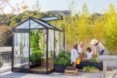 family tending to plants beside a greenhouse