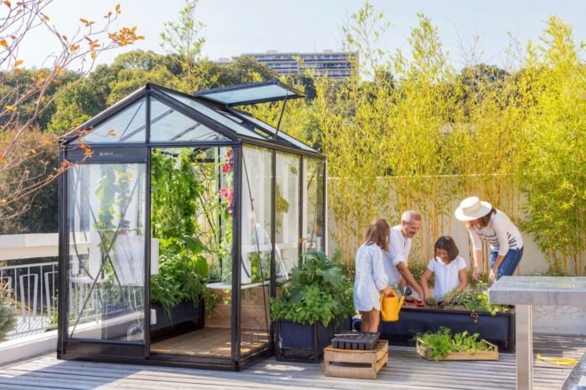 family tending to plants beside a greenhouse
