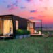 black tiny home with two wood decks on an island during a pink sunset