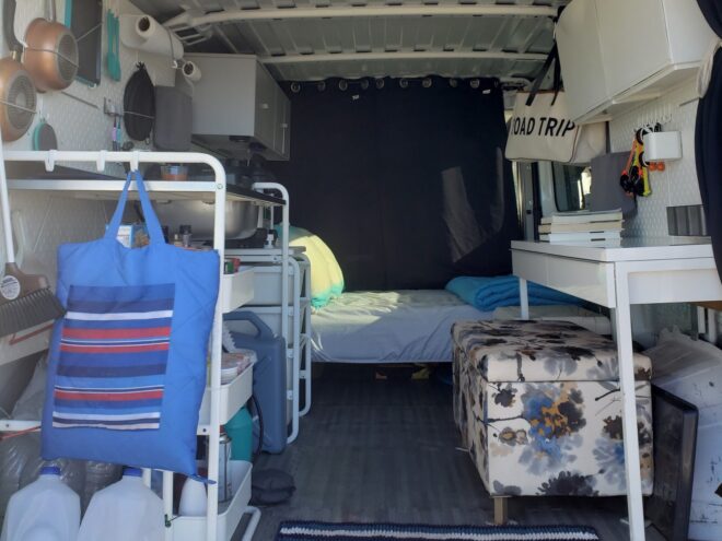interior space of converted van, showing organizational furniture and a bed towards the back of the van